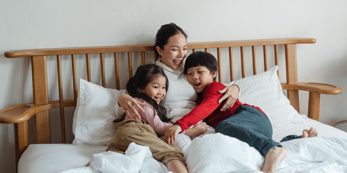 Young mother and children cuddling in bed.