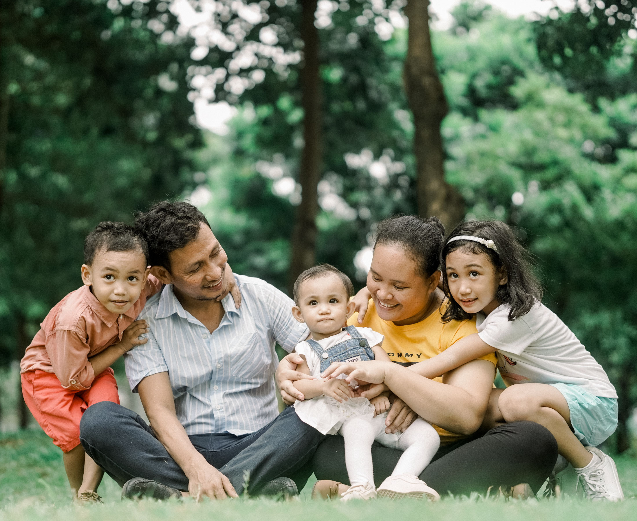 Southeast asian family sitting on grass,