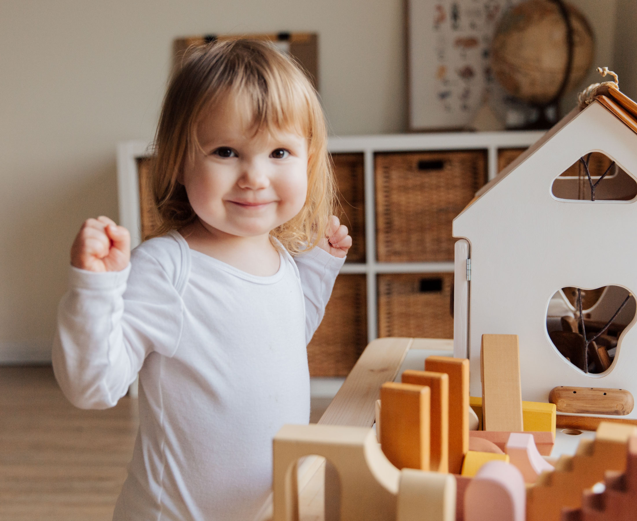 Young girl smiling next to building blocks.
